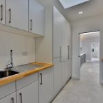 Closed kitchen design with an aluminum sink and white cabinets