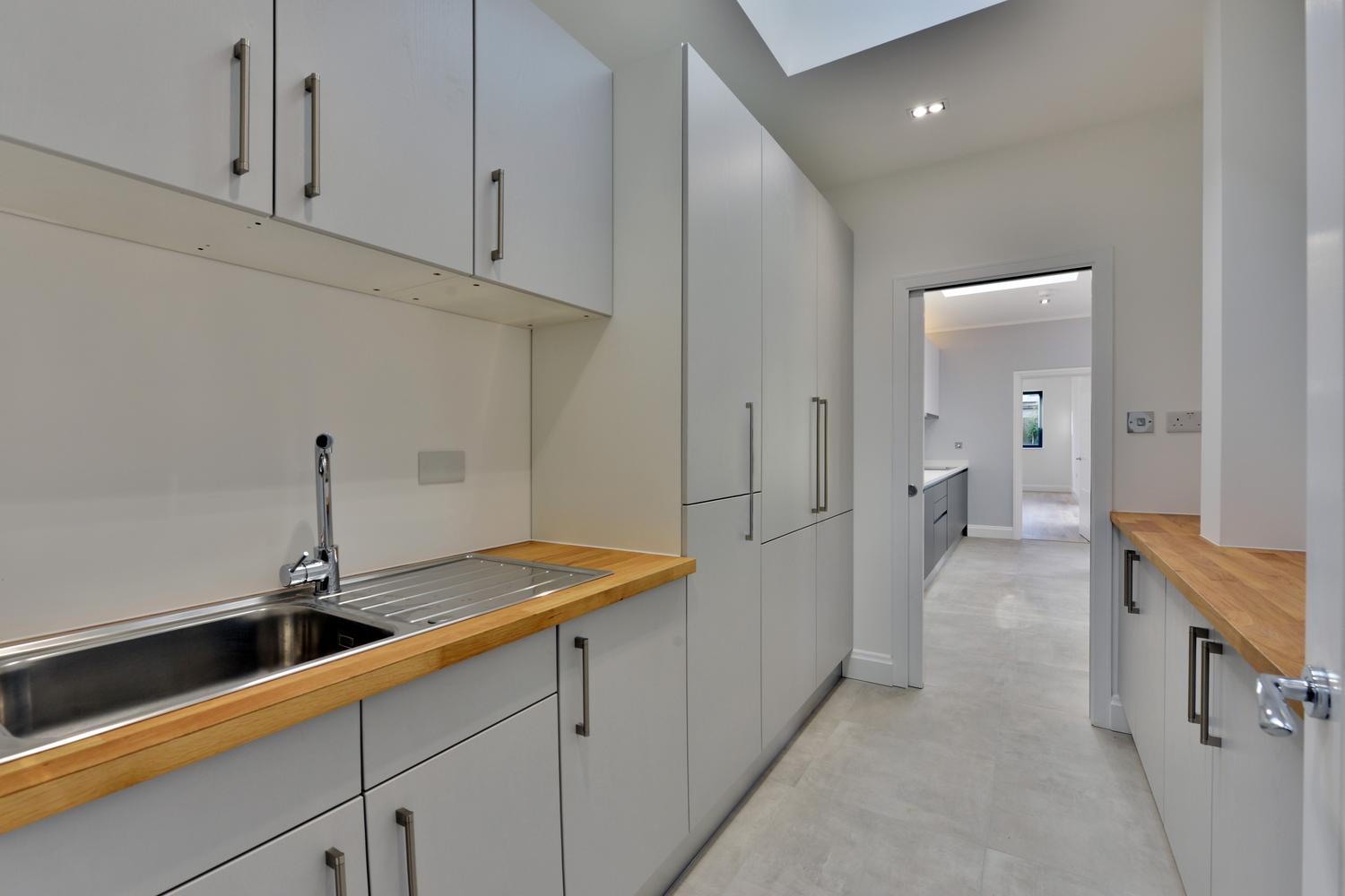 Closed kitchen design with an aluminum sink and white cabinets