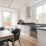 Closed kitchen design with a small dining table and couch