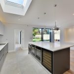 Open plan handleless kitchen design with vertical lightening