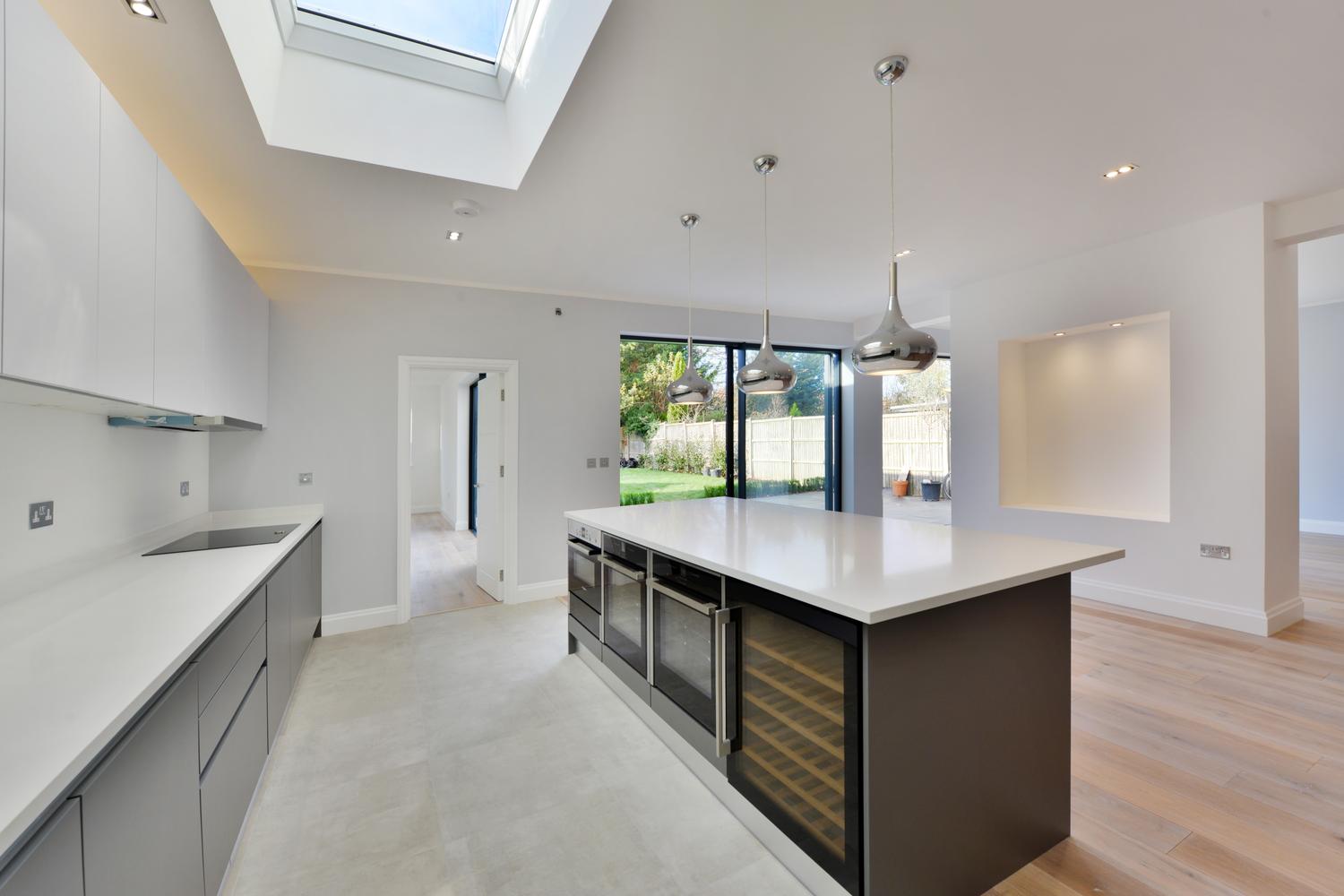 Open plan handleless kitchen design with vertical lightening